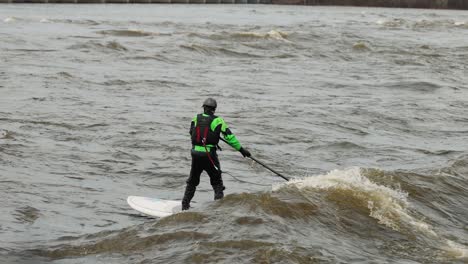 Mann-Surft-Während-Der-Hochwassersaison-Mit-Einem-Langen-Brett-Im-Kielwasser-Einer-Welle-Auf-Dem-Ottawa-River