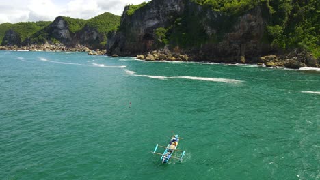 Indonesian-fishermen-in-small-fishing-boat-on-turquoise-ocean-by-Kesirat-cliffs