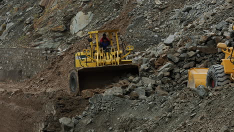 Wheeled-Bulldozer-Clearing,-Pushing-Soil,-And-Rocks-After-Landslide-Blocked-The-Karakoram-Highway-At-Dasu,-Pakistan
