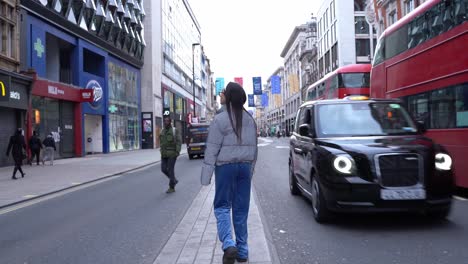 Beautiful-young-woman-walks-around-Soho,-London-looking-lost,-wide-shot