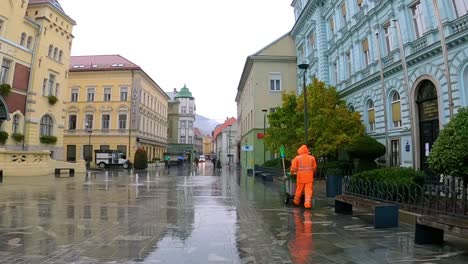 Limpiador-De-La-Ciudad-Caminando-Por-Una-Calle-Peatonal-En-Celje,-Eslovenia-Una-Mañana-Lluviosa