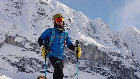 Smiling-skier-posing-for-photo-in-front-of-snowy-mountain-range