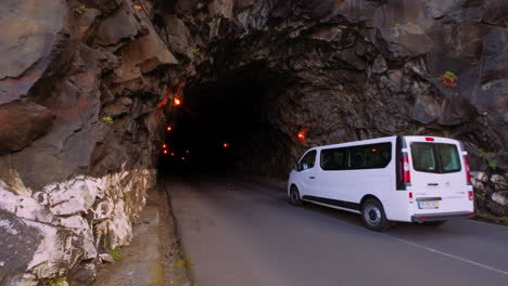 Slow-motion-shot-of-white-van-driving-into-dark-tunnel-of-mountain-on-Madeira-Road-Trip