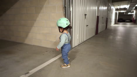 Adorable-Toddler-With-Green-Bike-Helmet-Walking-In-The-Garage---wide-shot