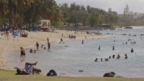 Menschen-Genießen-Die-Sonne,-Gehen-Spazieren-Und-Schwimmen-Am-Strand-In-San-Juan,-Puerto-Rico