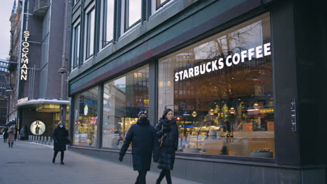 Menschen-Gehen-An-Stockmann--Und-Starbucks-Schildern-Auf-Der-Helsinki-Street-Vorbei,-Slomo