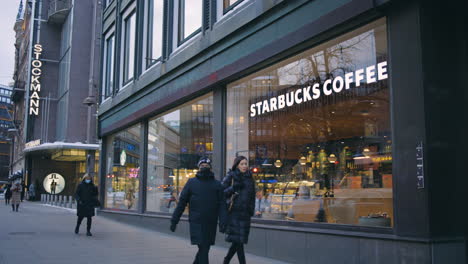 La-Gente-Camina-Por-Los-Carteles-De-Stockmann-Y-Starbucks-En-La-Calle-Helsinki,-Slomo