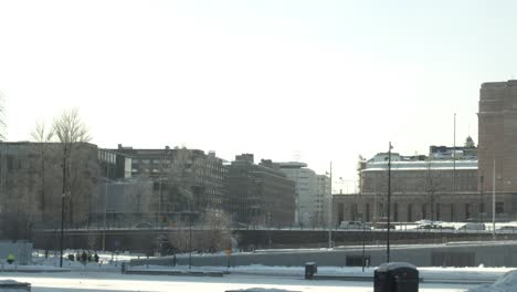 Wide-cityscape-time-lapse-of-central-library-square-in-Helsinki-snow-and-ice-on-the-streets,-bright-daylight