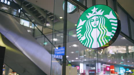 Slomo-Von-Starbucks-Logo-Auf-Schild-An-Glaswand-Und-Rolltreppe-Im-Einkaufszentrum