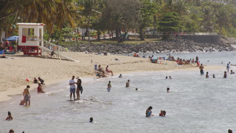 Toma-En-Cámara-Lenta-De-Personas-Nadando-Y-Jugando-En-Una-Playa-Llena-De-Gente-En-San-Juan,-Puerto-Rico