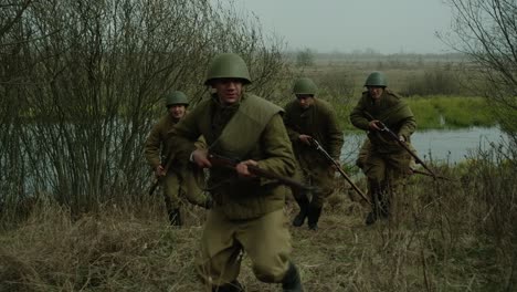 Soldiers-running-in-a-swampy-field-with-world-war-ii-rifles-and-one-wounded-soldier-touching-his-bloody-wound