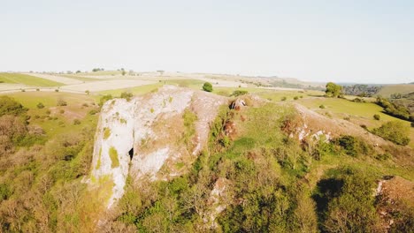 Sideways-aerial-drone-shot-showing-side-profile-of-Thor's-Cave,-Ashbourne,-Peak-District,-England
