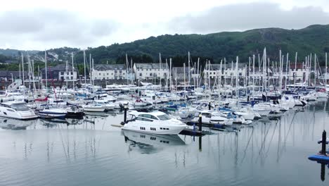 Expensive-collection-moored-yachts-and-sailboats-under-misty-mountain-harbour-waterfront-retirement-town-zoom-in