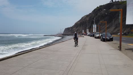 Video-4k-De-Un-Parapente-Y-2-Ciclistas-Haciendo-Deporte-Y-Viviendo-Un-Estilo-De-Vida-Saludable-En-Lima,-Peru,-Justo-En-La-Costa-De-Miraflores-Del-Oceano-Pacifico