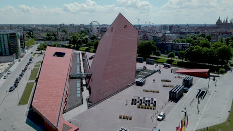 Bird's-eye-view-of-Gdansk-Museum-of-Second-World-War-and-city-panorama-on-background-on-a-cloudy-but-sunny-day---Aerial-orbiting