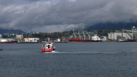 Fire-boat-checking-port-of-Vancouver-with-docking-container-ship-and-mystic-dark-cloudscape-in-background