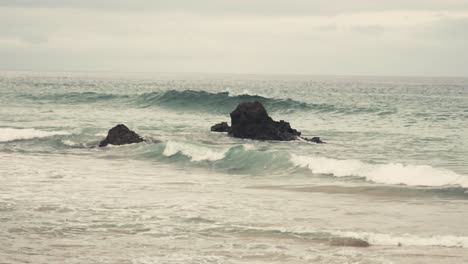 Kleine-Blaue-Wellen,-Die-An-Bewölkten-Tagen-Auf-Felsen-Im-Atlantischen-Ozean-Der-Portugiesischen-Algarve-Krachen