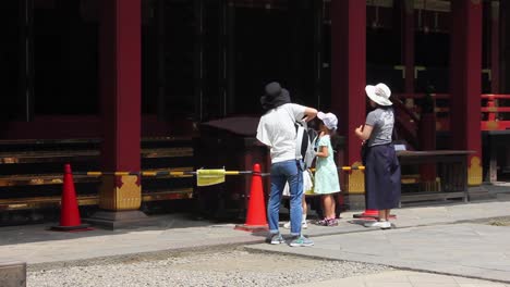 Family-praying-in-buddhist-temple-on-a-hot-summer-day