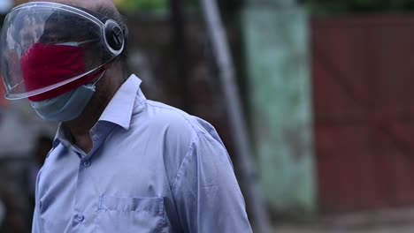 Old-Indian-man-wearing-mask-and-helmet-walks-on-road-during-covid-19-lockdown-and-corona-virus-quarantine