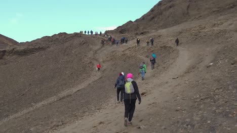 Onlookers-hikers-walking-on-mountain-near-erupting-volcano,-Iceland