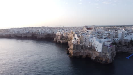 Waterfront-Buildings-On-Cliffs-In-Polignano-a-Mare-In-Puglia,-Italy-With-View-Of-Cliff-Diving-Ramp-At-The-Edge