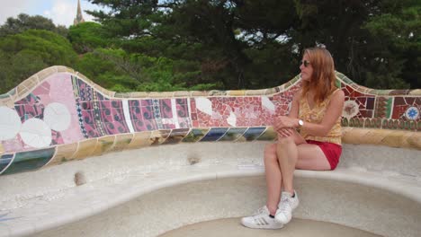 Eine-Moderne-Frau,-Die-Tagsüber-Im-Park-Güell-In-Barcelona-Ein-Schickes-Top-Und-Rote-Shorts-Sowie-Markenartikel-Wie-Adidas-Schuhe-Und-Eine-Wunderschöne-Armbanduhr-Trägt