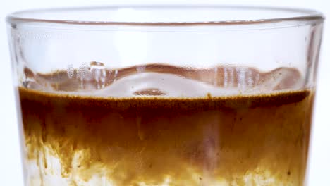 Macro-shot-of-instant-coffe-powder-dissolving-into-hot-water-in-a-transparent-glass,-macro-shot-close-up-view