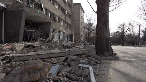 A-car-and-people-pass-a-hotel-that-was-hit-by-a-cruise-missile,-destroying-a-large-section-of-the-building-during-the-Russian-invasion-of-Ukraine