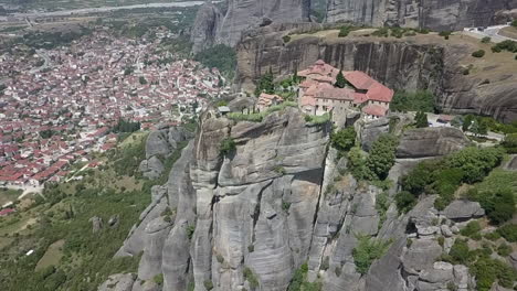 Birds-eye-view-of-cliff-top-monastery-high-above-Greek-town,-Kalabaka