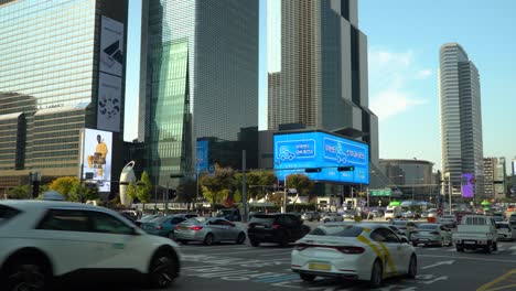 Centro-De-Comercio-Mundial-De-Seúl---Tráfico-De-Automóviles-Que-Pasa-Por-El-Cruce-De-La-Estación-De-Metro-De-Samseong-En-La-Carretera-De-Varios-Carriles-Más-Ancha-Cerca-De-La-Torre-Comercial-Coex-Y-La-Torre-Parnas-Al-Atardecer-En-Otoño