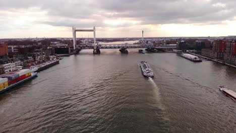 Luftaufnahme-über-Oude-Maas-Mit-Schiffen,-Die-Sich-Der-Eisenbahnbrücke-Spoorbrug-Gegen-Den-Sonnenunterganghimmel-In-Dordrecht-Nähern