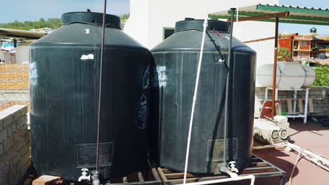 Two-water-tanks-with-pipes-and-taps-for-storage-and-water-supply-on-roof-in-Mexico