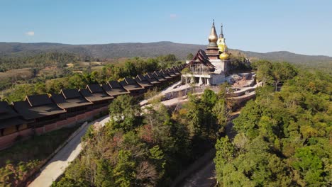Aerial-footage-sliding-to-the-right-revealing-the-entrance-of-the-famous-temple-Wat-Somdet-Phu-Ruea-while-people-going-out-of-the-door-also-showing-the-Ming-Mueang-landscape,-Loei-in-Thailand