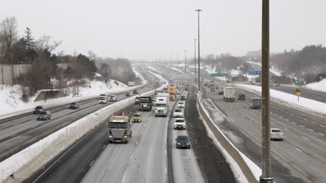 Toma-Estática-De-Camiones-Conduciendo-Por-La-Carretera-Ondeando-Banderas-Canadienses,-Camioneros-Con-Carteles-De-Protesta-Se-Reúnen-Por-La-Carretera-Con-El-Tráfico-De-La-Ciudad