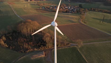 Aerial-footage-of-a-large,-white-wind-turbine-in-North-Rhine-Westphalia,-Germany-during-a-sunset-in-winter