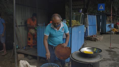 Man-with-face-mask-cooking-corn-in-rustic-shop,-Sri-Lanka