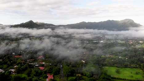 Low-clouds-cover-town-of-Valle-de-Anton-in-central-Panama-located-in-extinct-volcano-crater,-Aerial-wide-angle-flyover-shot