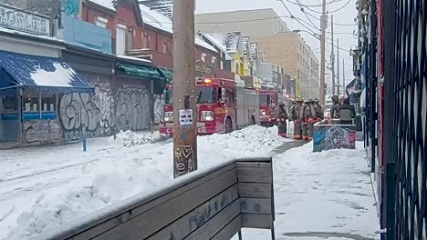 Firefighters-in-front-of-Jimmy's-Coffee-on-Baldwin-Street,-Kensington-Market,-Toronto,-during-snowfall