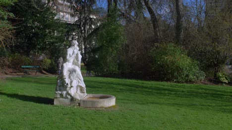 Gente-Paseando-Por-El-Parque-Montsouris-Con-Esculturas-De-Piedra-Blanca-En-París,-Francia
