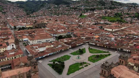 Vista-Panorámica-De-Una-Plaza-De-Armas-Desierta,-La-Ciudad-De-Cusco-Y-La-Montaña-De-Los-Andes-En-El-Fondo---Disparo-De-Dron-Panorámico-Hacia-Adelante