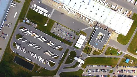 Aerial-top-down-view-of-the-big-logistics-park-with-warehouses,-loading-hub-and-a-lot-of-semi-trucks-with-cargo-trailers-awaiting-for-loading-unloading-goods-on-ramps