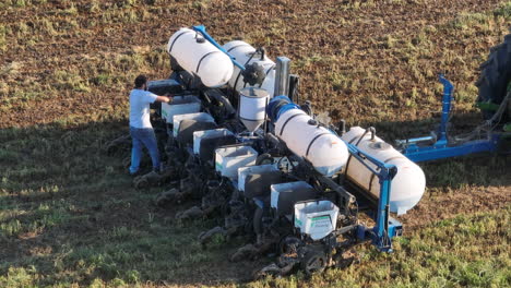 Aerial-zoom-from-drone-of-American-farmer-using-scoop-to-fill-planter