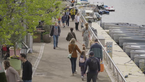 People-enjoy-beautiful-day-walking-near-Thames-river-in-London,-slow-motion-view