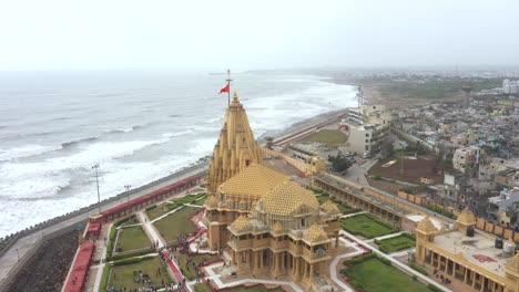 Aerial-drone-rotating-shot-of-Somnath-mandir-with-cityscape-and-sea-in-the-background