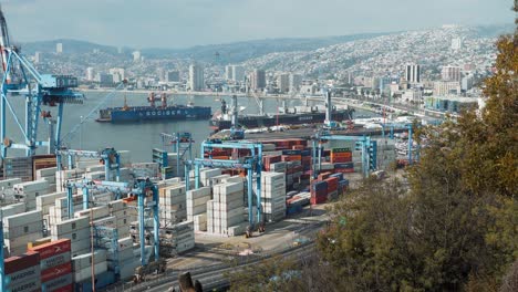 Static-shot-of-Valparaiso-Sea-Port-cranes-and-containers,-cargo-ships-ready-to-be-loaded,-hillside-city-in-background,-Chile