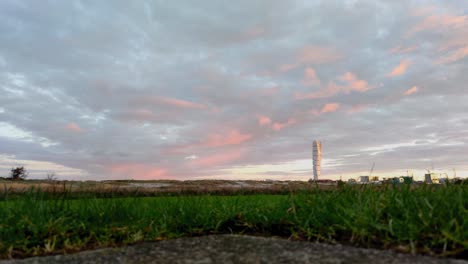 View-of-Turning-Torso-In-Malmö-From-a-Green-Area-With-Grass-In-The-Foreground-and-Pink-Sky