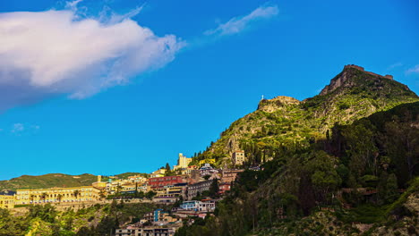 Low-angle-shot-of-Beautiful-mediterranean-sicilian-coastal-town-with-houses-and-homes-over-a-hilly-terrain-in-Sicily,-Italy-at-daytime-in-timelapse