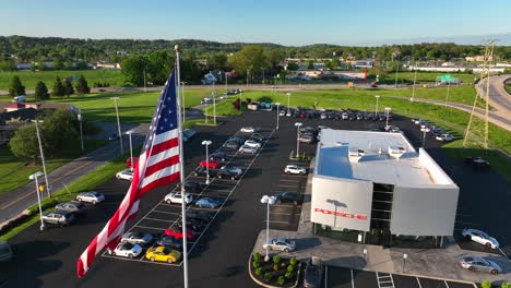 Aerial-view-of-American-flag-waving-in-front-of-Porsche-dealership