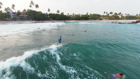 Aerial-FPV-drone-shot-of-people-surfing-in-the-sea-with-sunset-in-the-background