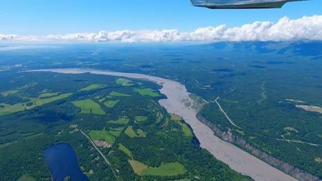 Small-airplane-flight-over-the-glacier-silt-filled-Matanuska-River-with-the-Talkeetna-Mountain-range-in-the-distance,-near-Palmer-Alaska